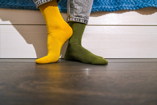 Mismatched yellow and green socks on wooden floor, Day of Different Socks concept, individuality personality and self expression