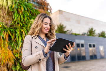 Fototapeta premium Young woman smiling using tablet outdoor urban area