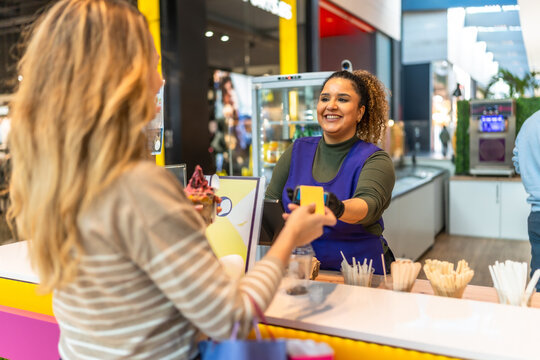 Woman paying cashier with credit card at ice cream shop