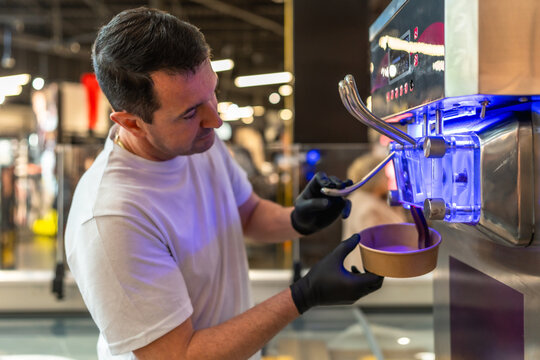 Man serving soft serve ice cream from machine