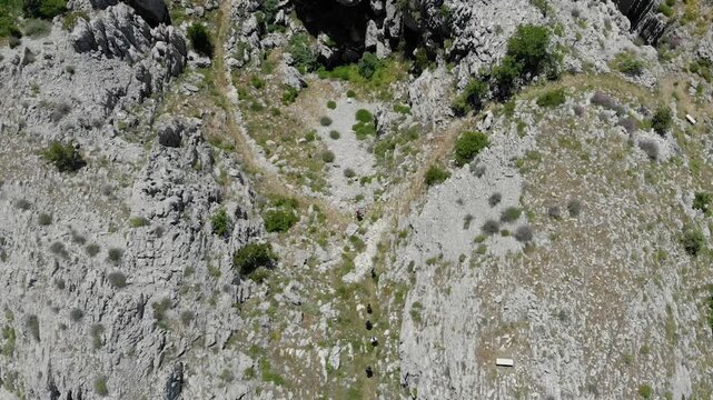 Top-down drone footage of hikers walking between rugged rocks in Arz Jaj, Lebanon. Ideal for hiking, adventure travel, exploration, fitness, and outdoor lifestyle campaigns.
