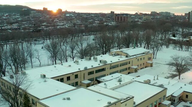 drone overlooking main front building in parc lafontaine, montreal, quebec, canada in winter n some long sunset