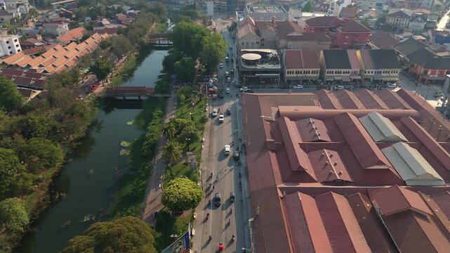 Aerial drone video of Siem Reap Riverside showing river road traffic buildings and urban greenery capturing daily city life and travel atmosphere in Cambodia
