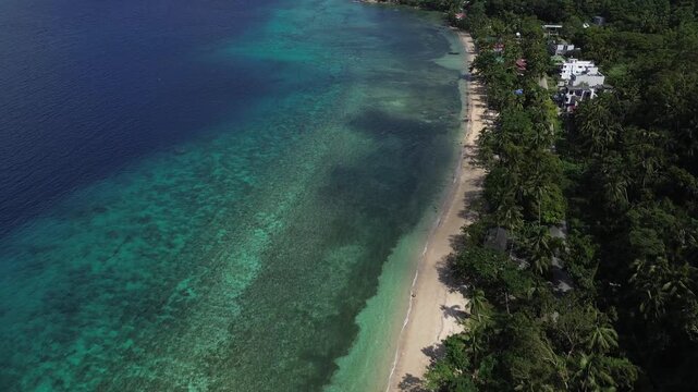 Drone aerial over Romblon Island showcasing crystal clear turquoise water, rolling green hills and vibrant blue sky. Untouched tropical landscape in the Philippines with pristine coastline.