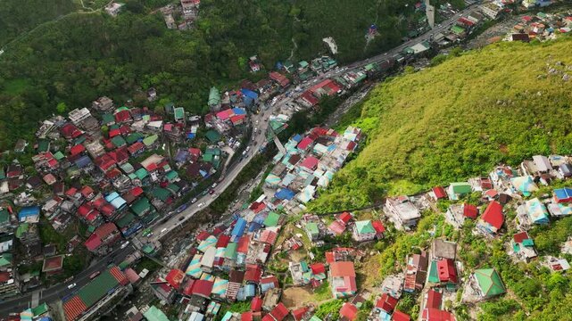 Aerial pullback of the StoBoSa Hillside Homes Artwork at Valley of Colors in La Trinidad, Benguet with painted residential houses along a busy mountain road