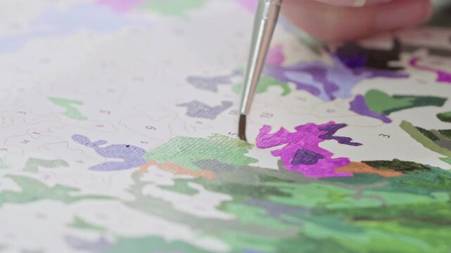 Woman enjoying a productive weekend afternoon with a paint-by-numbers kit. Relaxing leisure activity and quality time spent on creative hobbies.