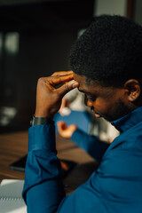 Stressed black man suffering headache at work
