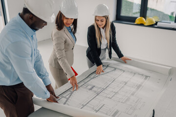 Architects and engineers reviewing blueprints on construction site