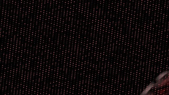 Black background with repeating pink dots arranged diagonally, with blurred red shape on the left