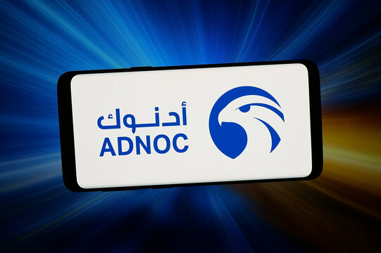 Stuttgart, Germany - 02-16-2026: In this photo illustration, the logo of  Abu Dhabi National Oil Company (ADNOC) is displayed on a smartphone in front of abstract background on computer screen.