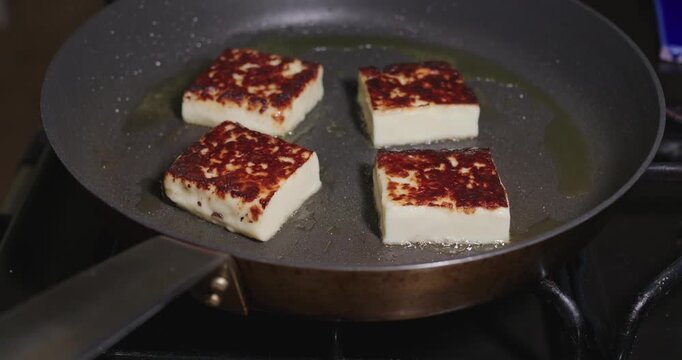 Four squares of cheese fry in a hot skillet