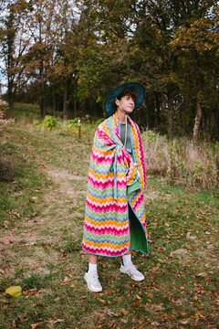 Teen boy in nature on hike in forest with blanket around shoulders