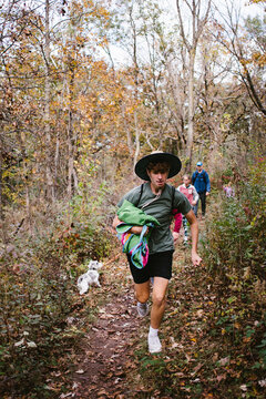 Teen boy in hat running along fall forest path on hike