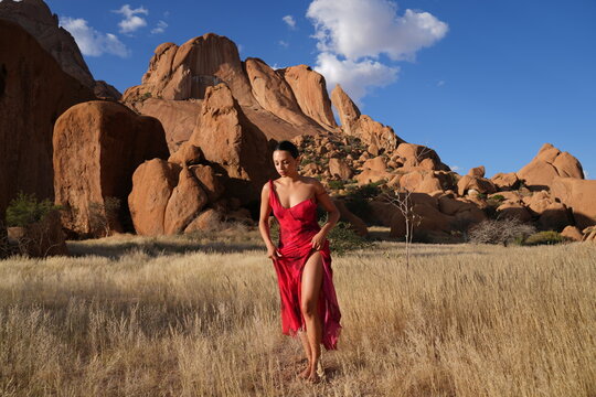 Young woman in red dress with dramatic mountain backdrop