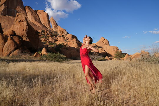 Young woman in red dress with dramatic mountain backdrop