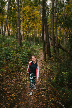 Blond tween girl happy hiking on fall forest path