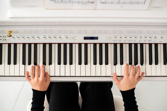 teenager's hands are playing on a digital piano, top view.