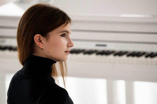 face of teenage girl against of the keyboard of white grand piano