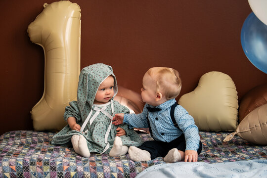 Two a baby sitting together, celebrating first birthday at home.