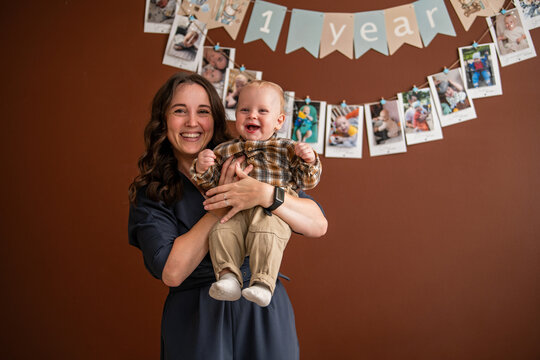 Woman holding cheerful baby boy celebrating his first birthday
