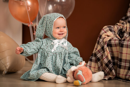 Happy baby girl with blue eyes sits on floor with stuffed toy bunny