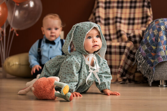 baby girl and boy crawling on floor during 1st birthday celebration.