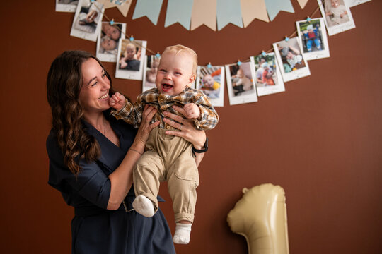 Woman holding cheerful baby boy celebrating his first birthday