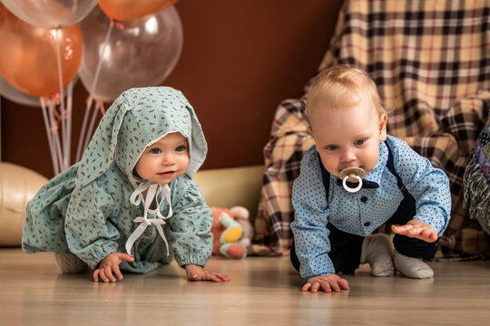 baby girl and boy crawling on floor during 1st birthday celebration.