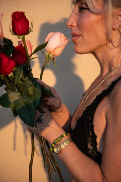 woman smelling bouquet of roses at dusk