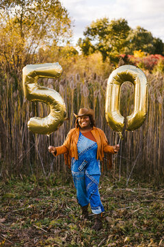Black adult woman in cowboy outfit with 50 year old balloons