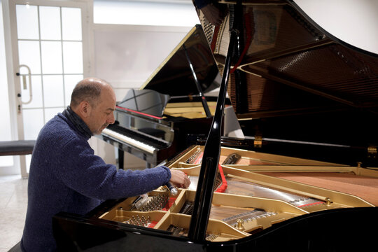 Piano technician adjusting grand piano strings