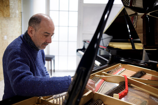 Piano technician adjusting grand piano strings