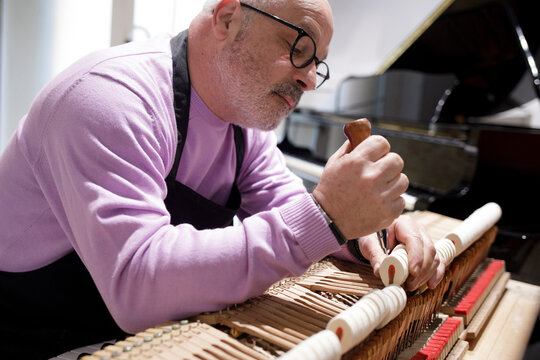 Piano technician repairing acoustic piano mechanism