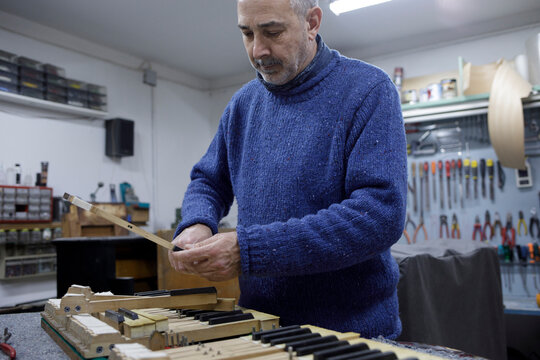 Piano technician adjusting keyboard mechanism in shop