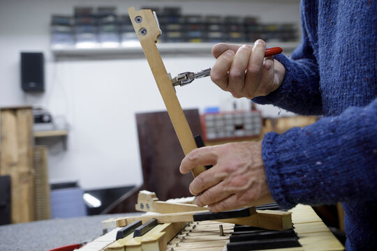 Piano technician adjusting keyboard mechanism in shop