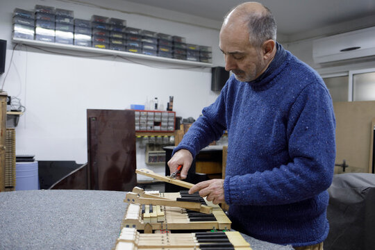 Piano technician adjusting keyboard mechanism in shop