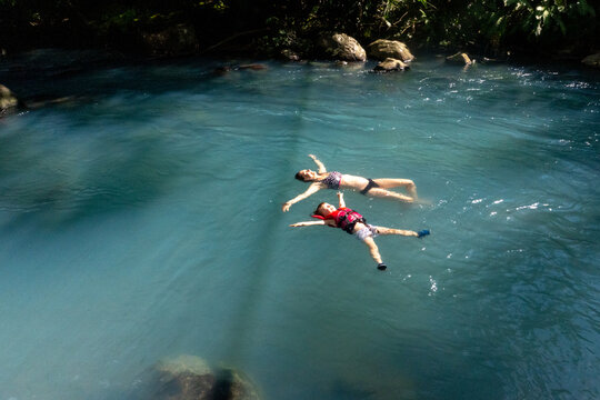 A mother and her son float on their back in a turquoise river.