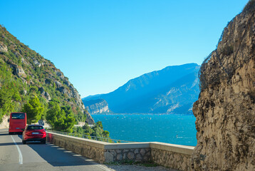 Bus and car driving at gardesana road, view to lake Gardasee and mountains