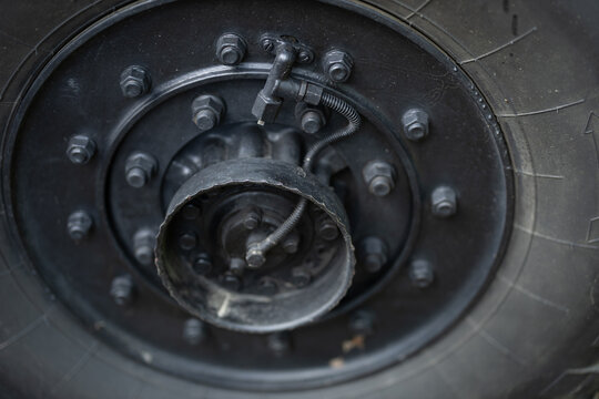 This close-up shows a heavy-duty black industrial wheel featuring a Central Tire Inflation System CTIS . The mechanical hub is secured with numerous bolts and connected by a flexible hose.