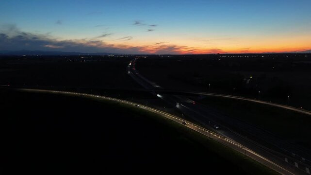 Aerial footage of a tall telecommunication tower equipped with antennas and satellite dishes, transmitting signals against a clear dark blue sky at dusk in a rural landscape