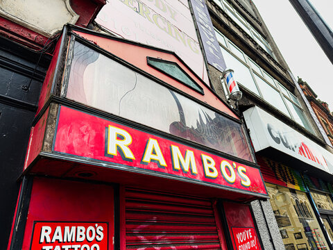 Rambo's Tattoo with red sign and barber pole in Manchester city street