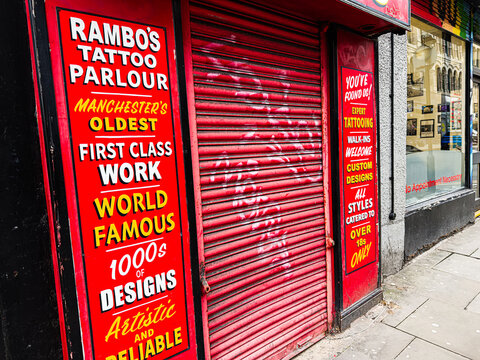 Rambo's Tattoo Parlour storefront in Manchester with red shutter and bold vintage signs