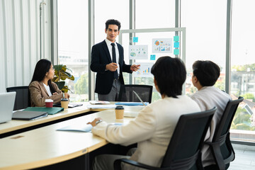 Startup team analyzing financial report during conference meeting. Presenter guiding discussion using chart board. Corporate teamwork, leadership skills, business planning concept.