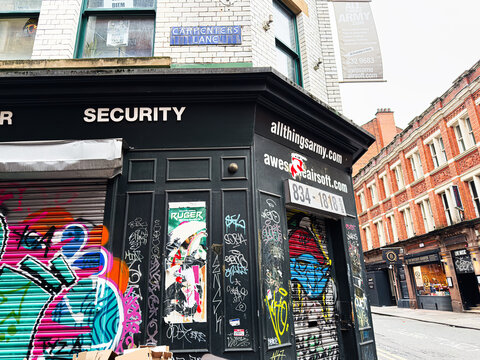 Security storefront in Manchester Street with graffiti shutters and urban shopfront signs on brick building