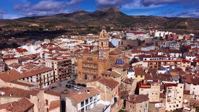 Aerial view of Chelva old town centered on the historic Lady of the Angels Church, showing baroque architecture, tiled roofs, and mountainous Valencian landscape.