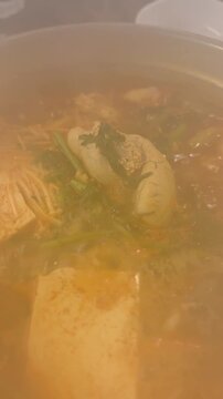 Boiling Korean spicy fish roe soup (Al-tang) with fresh pollack roe and vegetables in a stone pot