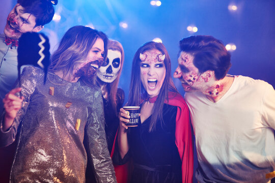 Friends in Halloween costumes dancing among confetti