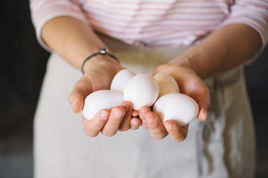 Woman holding raw white eggs