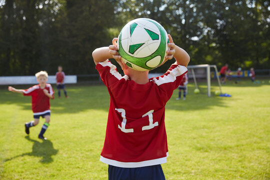 Soccer boy throwing ball on field