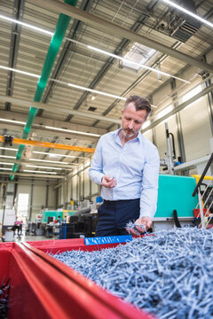 Man in factory examining shred in container